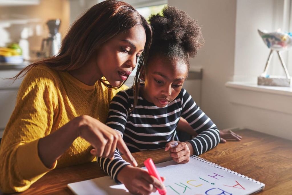 Mother doing homework with young daughter