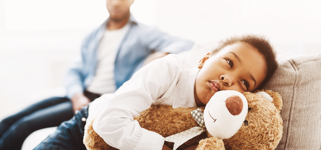 Child holding Teddy bear on couch