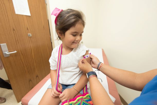 Child getting a bandage after a shot in a provider's office.
