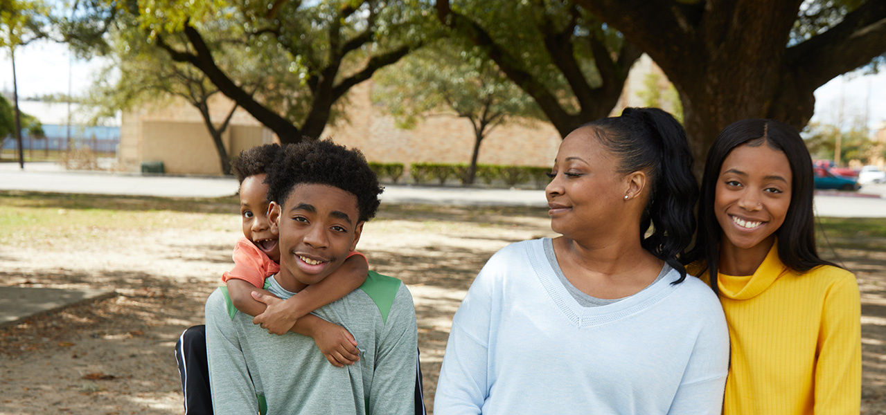 Family of four at the park smiling at each other