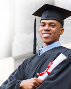 Young man in a graduation cap and gown holding a diploma