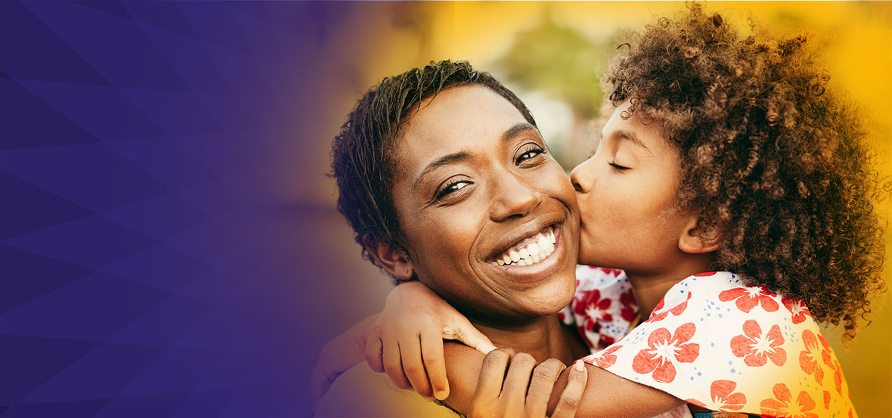 Daughter kissing her mother on the cheeck with purple background.