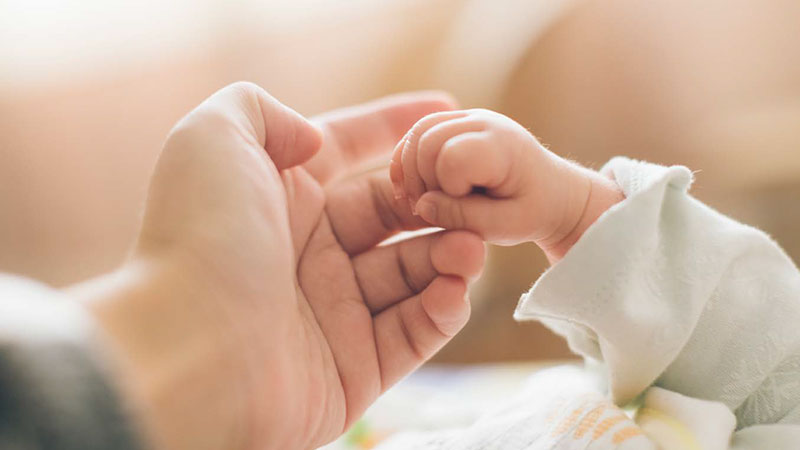 Mother and newborn holding hands