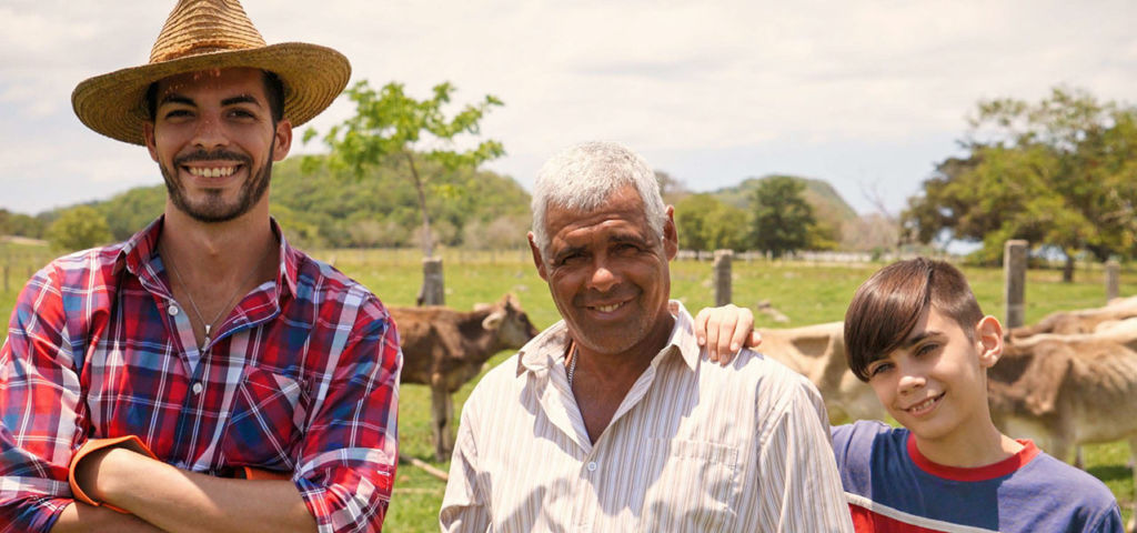 Farming father, son, and grandfather in a field with cows