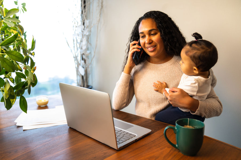 Mother holding child while on computer and phone