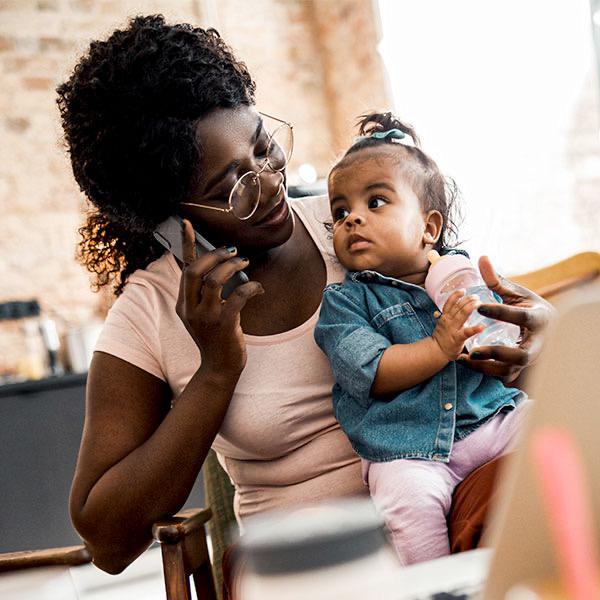 Mother talking on phone holding daughter