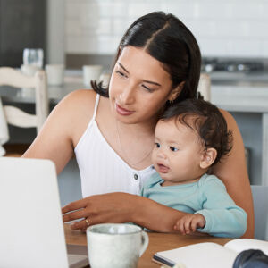 Hispanic mom with baby looking at a computer screen.