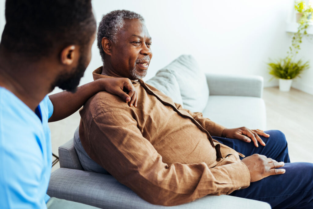 Caregiver consoling a senior male patient in a nursing home during the day.