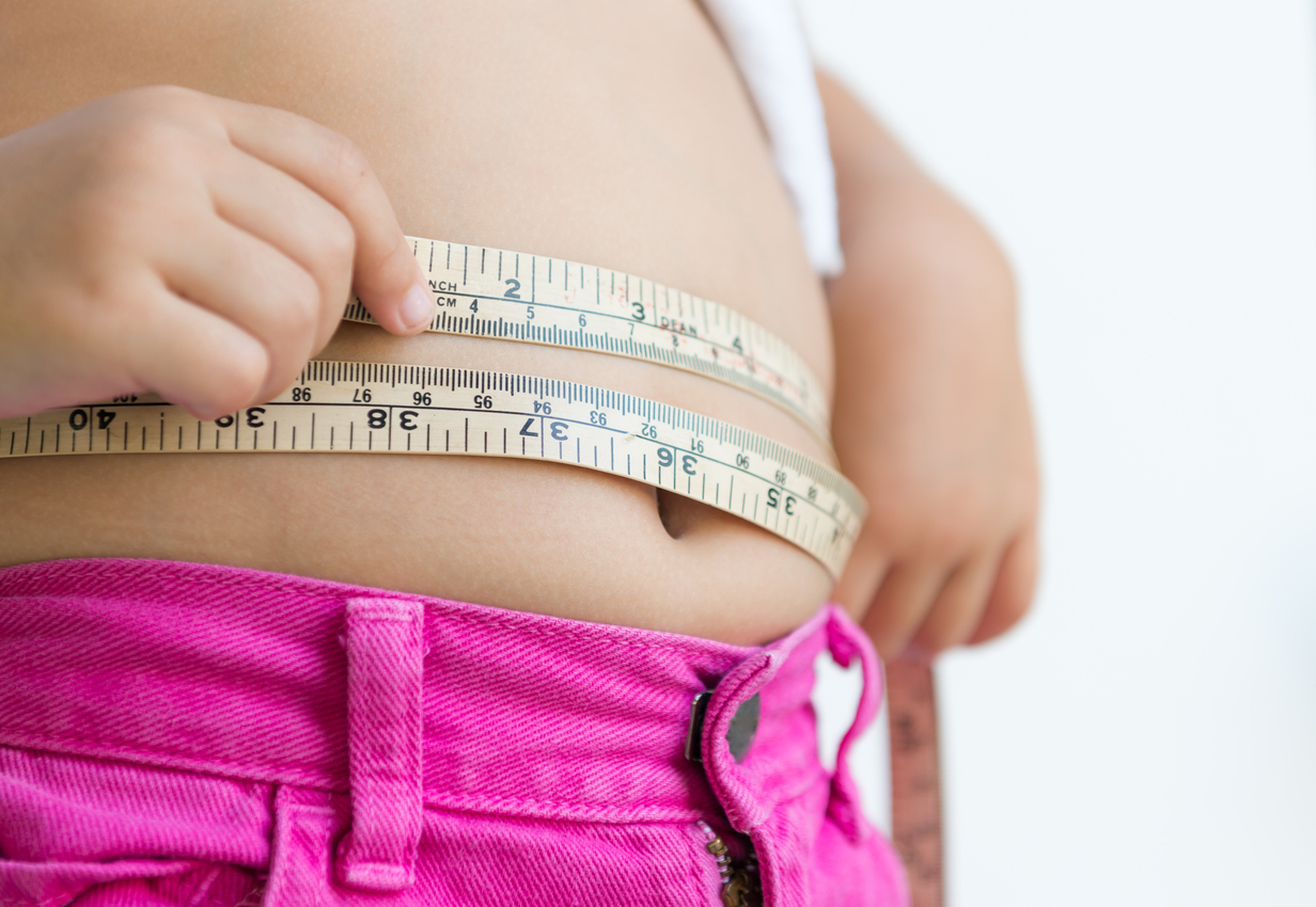 girl measuring her belly with measurement tape at home