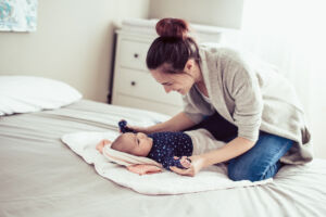 Young mother playing with her baby girl. Mother playing with baby on bad.